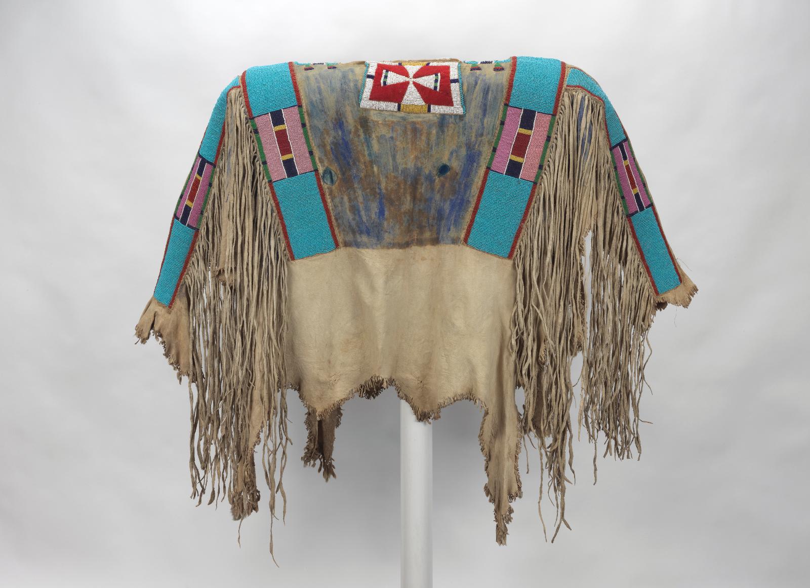 A Crow war shirt decorated with beaded strips and leather fringes.