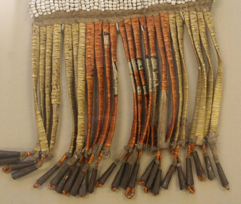 A row of rawhide strips wrapped with quills forms the bottom of a pipe bag. The visible knots are areas where the individual quills are spliced.