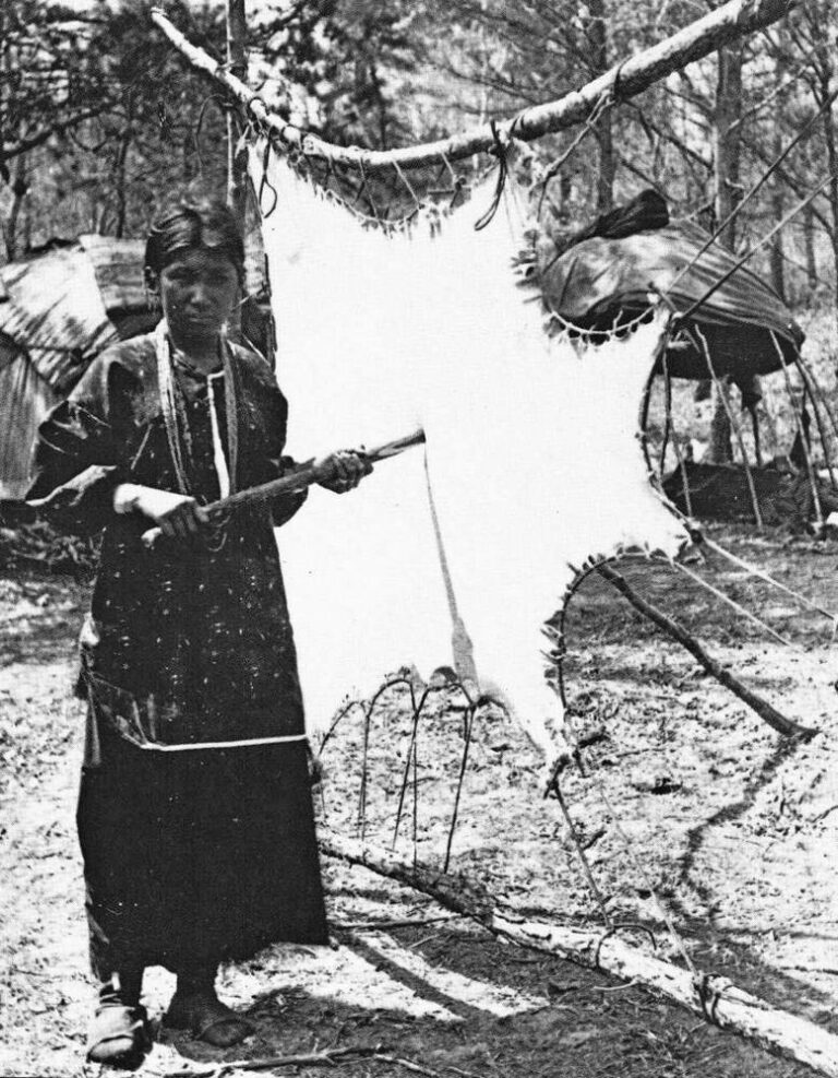 A Winnebago Indian woman softens leather in a frame.